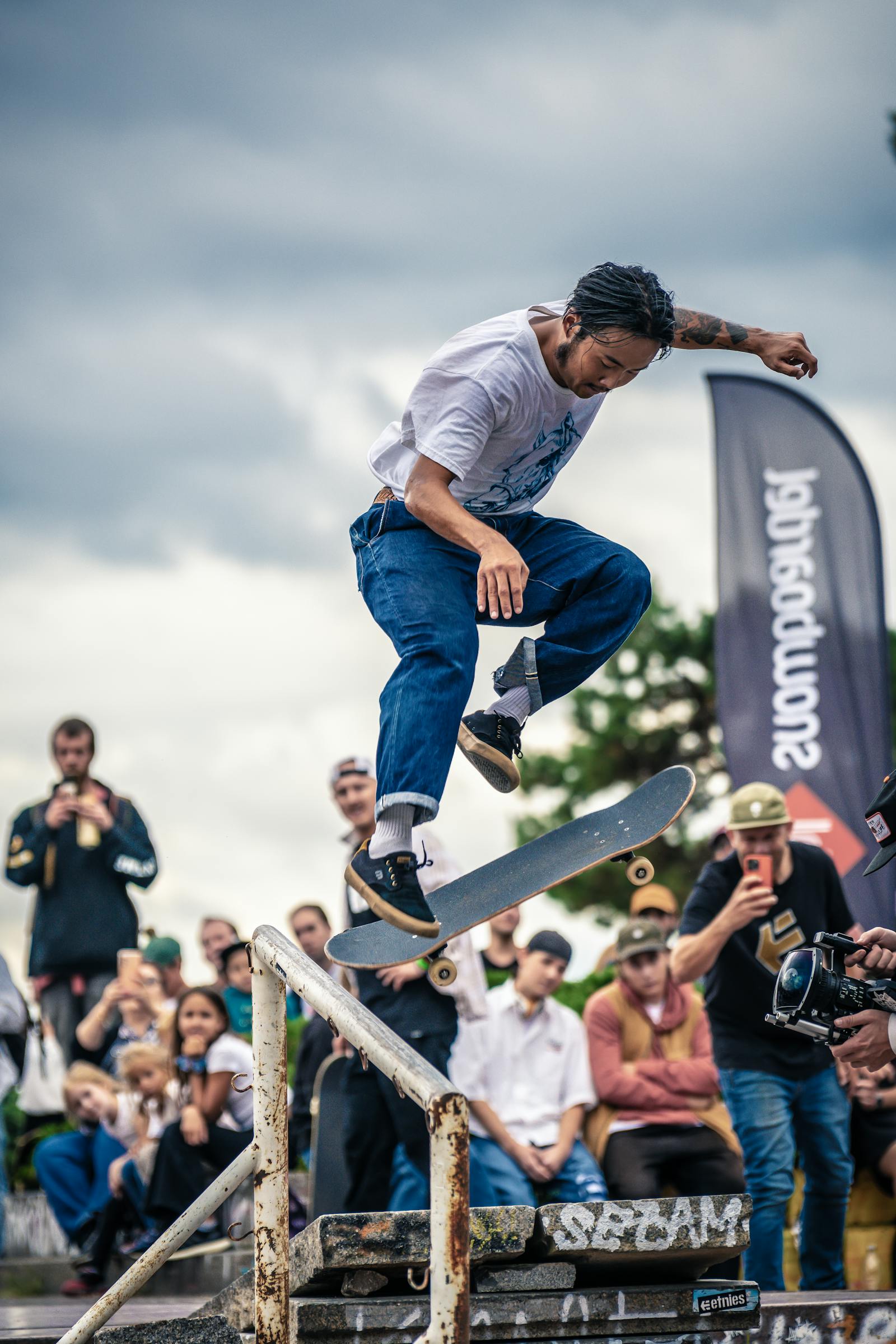 Skater catching a trick over a rail while the crowd watches